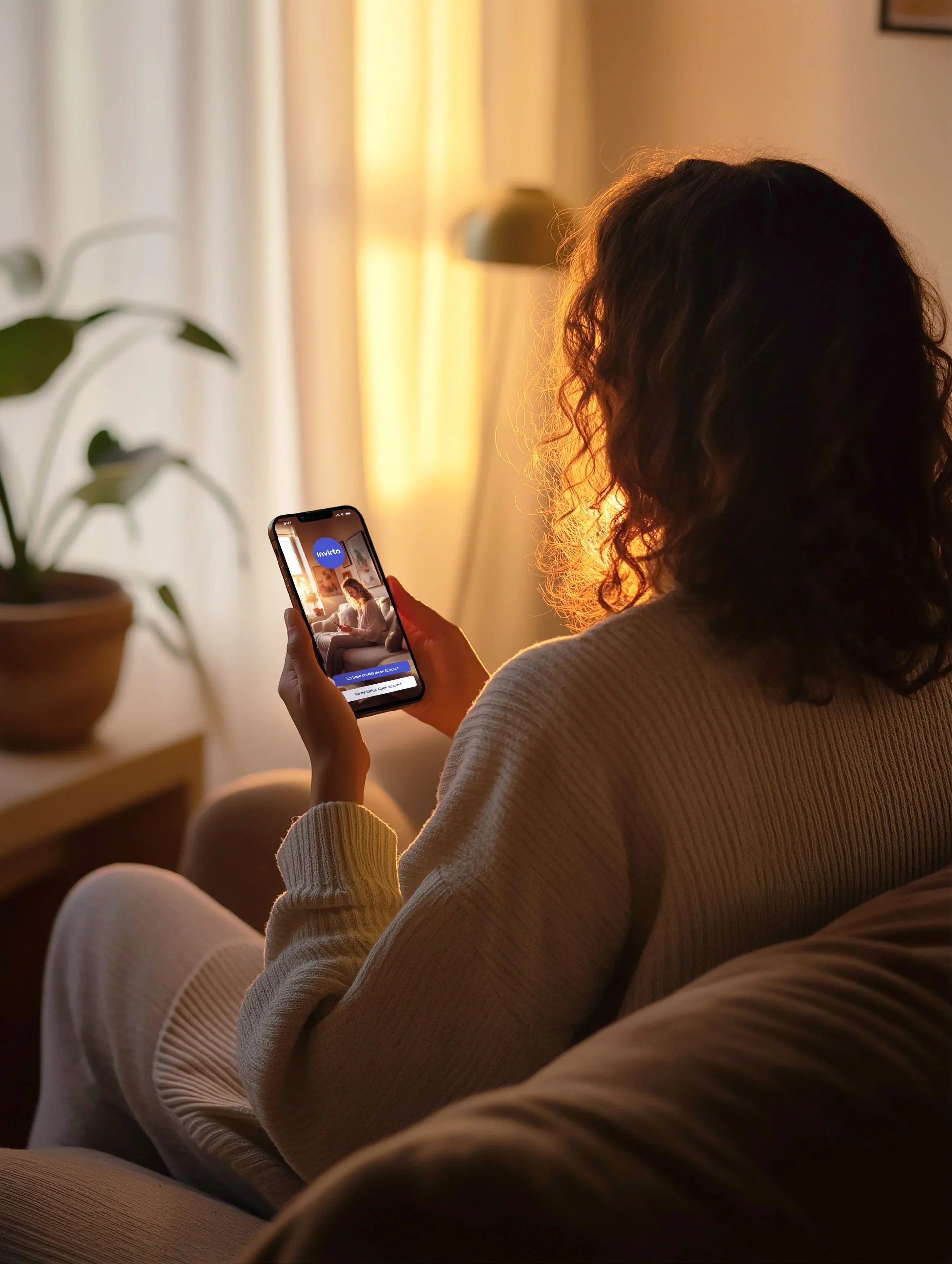 Frau sitzt bei warmen Licht und benutzt die Invirto App